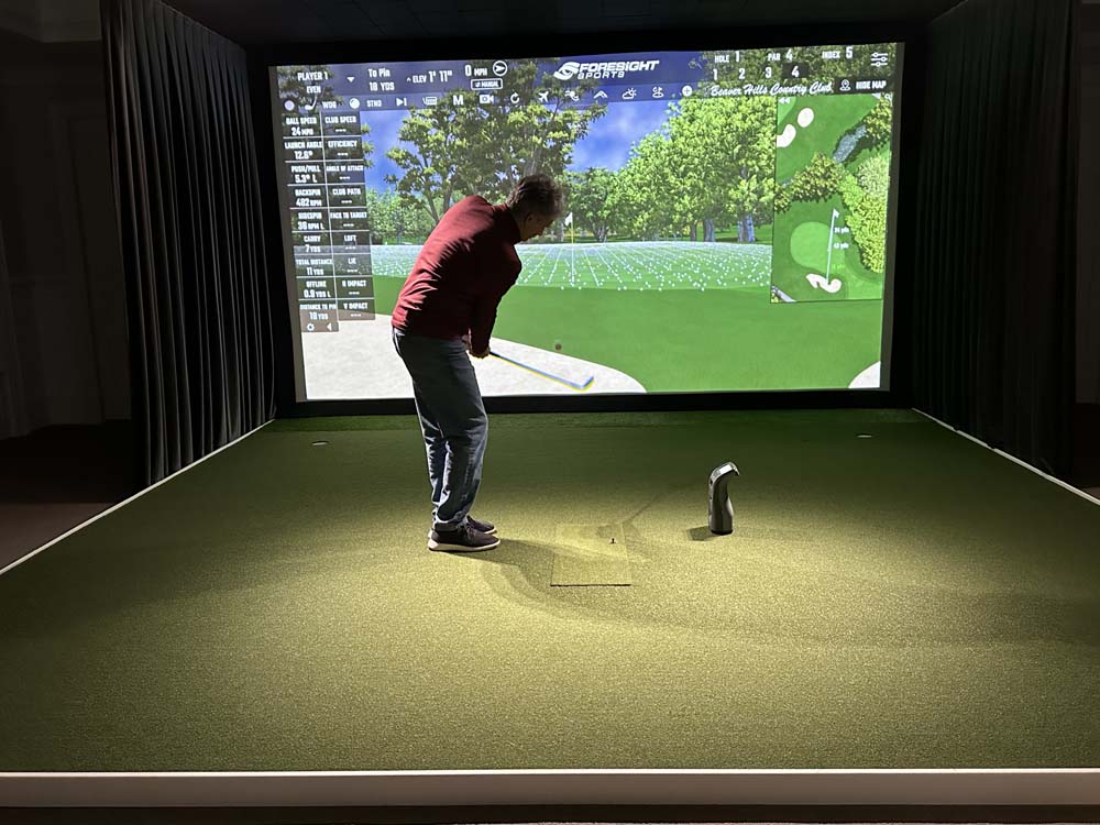 Man hitting on basement golf simulator