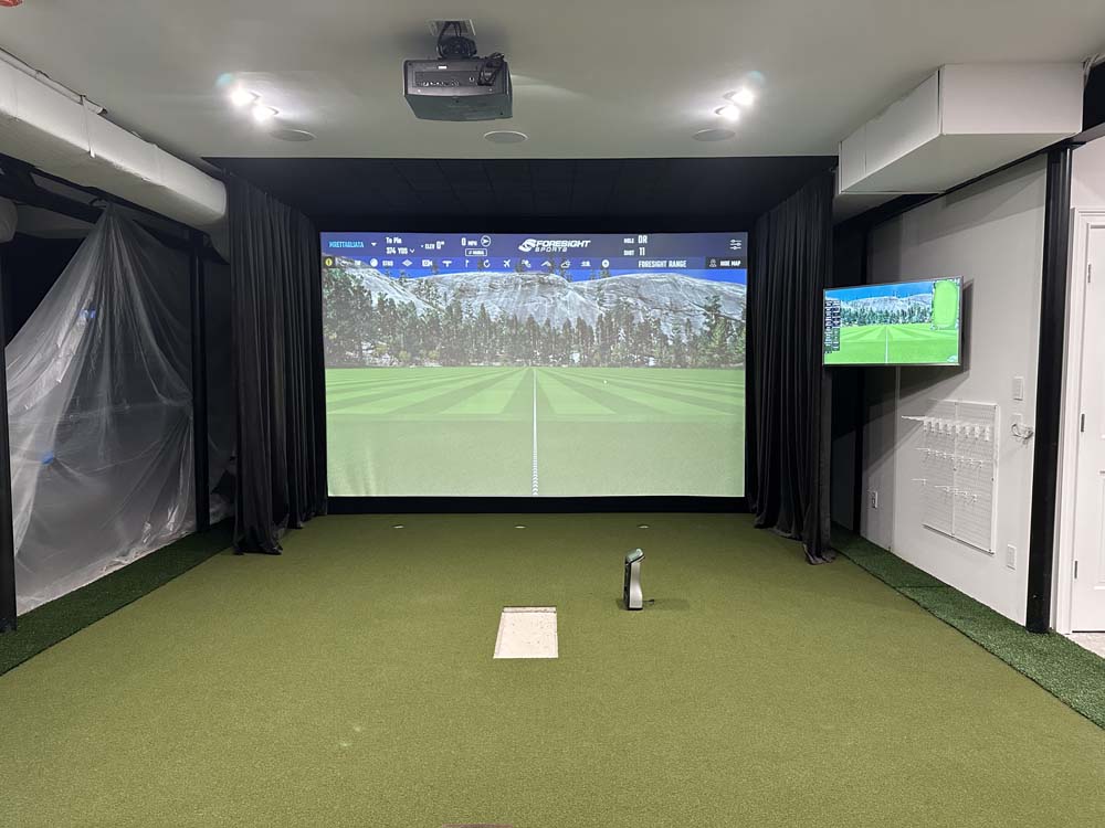 Home golf simulator with launch monitor sitting on turf